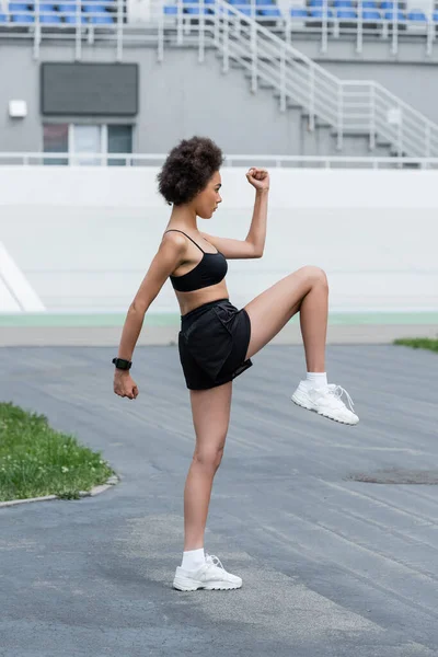 Side view of african american sportswoman with fitness tracker training on stadium - foto de stock