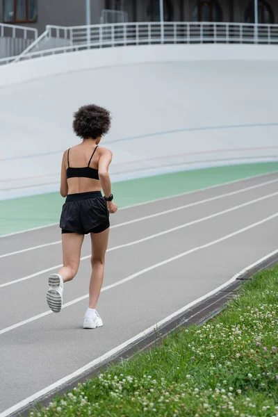 Back view of african american sportswoman running on track of stadium — Stock Photo