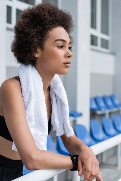 Африканская американская спортсменка с полотенцем, смотрящая на открытый стадион — стоковое фото