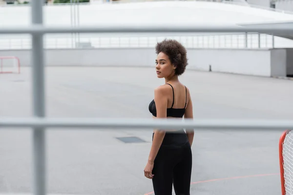 African american sportswoman in black sportswear standing on stadium — Stockfoto