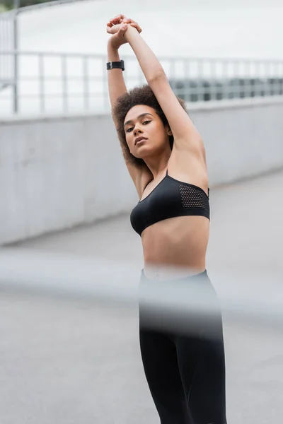 African american sportswoman warming up and looking at camera on stadium — Stockfoto