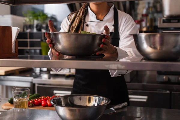 Cropped view of tattooed african american chef holding bowl in professional kitchen — Photo de stock