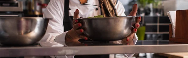 Cropped view of tattooed african american woman holding bowl in professional kitchen, banner — Photo de stock