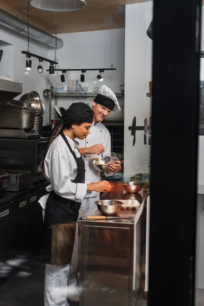 Cheerful multiethnic chefs cooking together in professional kitchen — Stock Photo