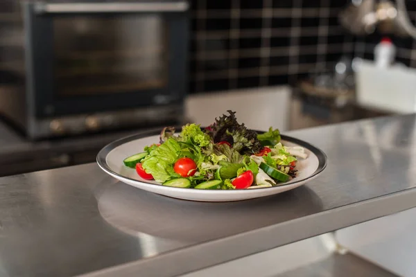 Plate with freshly cooked salad in professional kitchen — Stock Photo