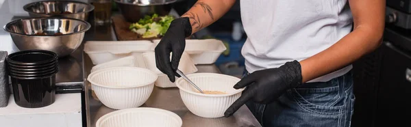 Cropped view of tattooed african american woman holding plastic bowl with soup in kitchen, banner — Fotografia de Stock