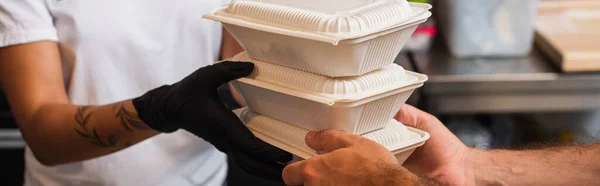 Cropped view of african american volunteer giving plastic containers with food to man, banner — Stock Photo