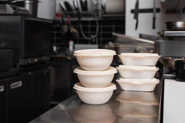 Plastic containers and bowls with prepared food for charity in kitchen - foto de stock