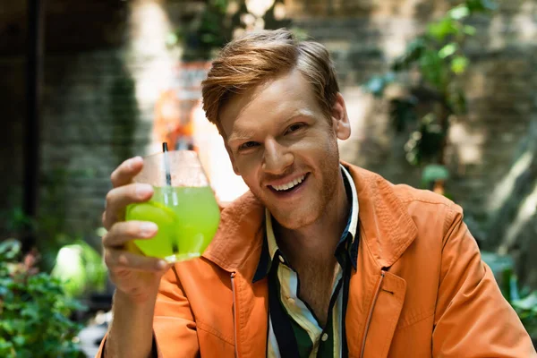 Happy redhead man holding glass with cocktail in outdoor terrace of bar — Photo de stock