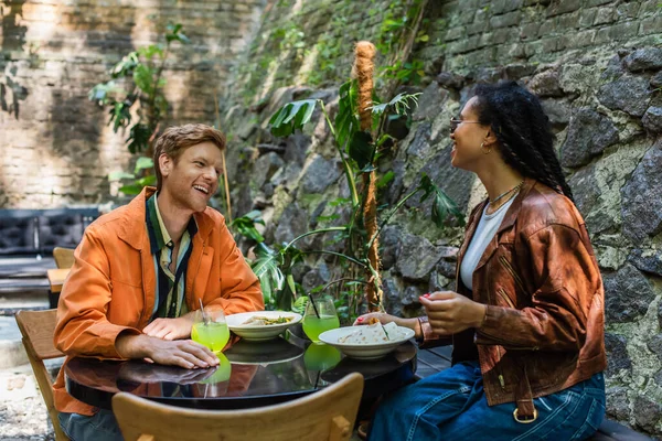 Happy multiethnic friends smiling while having lunch together in outdoor cafe terrace — Fotografia de Stock