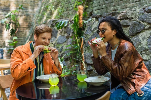 Young interracial friends eating quesadillas while having lunch in outdoor cafe terrace — Stockfoto