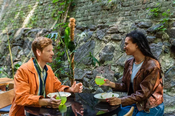 Cheerful multiethnic friends smiling while having lunch together in outdoor cafe terrace — Fotografia de Stock