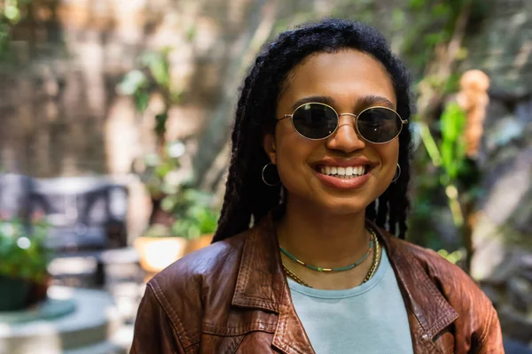 Portrait of happy african american woman in sunglasses smiling outside — Stock Photo