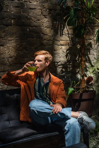 Young redhead man in leather jacket drinking green cocktail outside — Fotografia de Stock