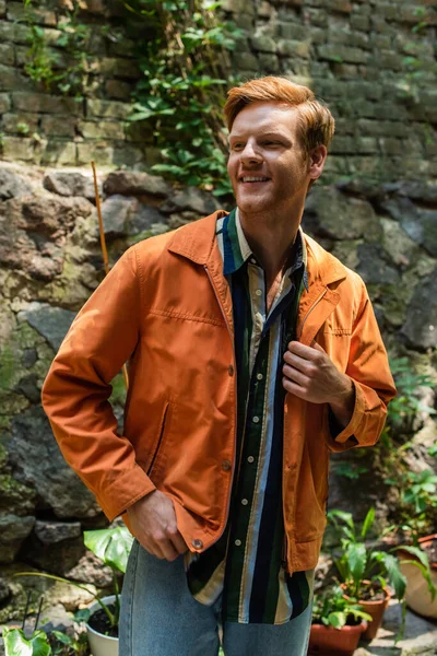 Happy redhead man in orange jacket smiling outside - foto de stock