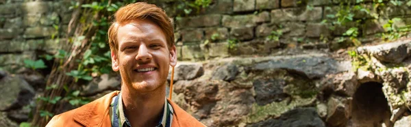 Cheerful redhead man in orange jacket smiling outside, banner — Photo de stock