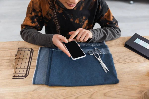 Cropped view of african american craftswoman taking photo on smartphone near cloth and sewing pattern — Stock Photo