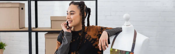 Positive african american designer talking on cellphone near mannequin, banner — Stock Photo
