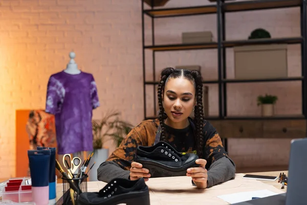 African american craftswoman holding shoe near sewing pattern and devices — Fotografia de Stock