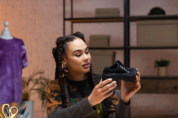 Smiling african american designer holding shoe in workshop — Stock Photo