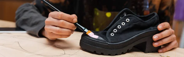 Partial view of african american craftswoman painting on shoe on sewing pattern, banner — Stock Photo