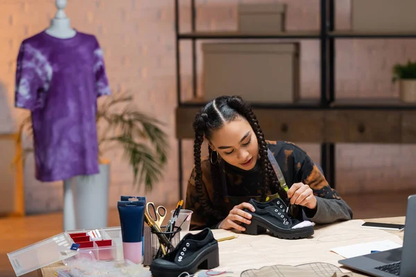 Африканський американський дизайнер малює на взутті біля гаджетів і шиє візерунок — стокове фото