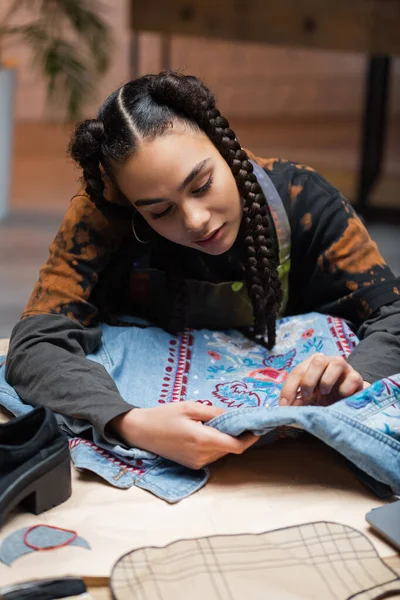 African american designer embroidering denim jacket in workshop — Photo de stock