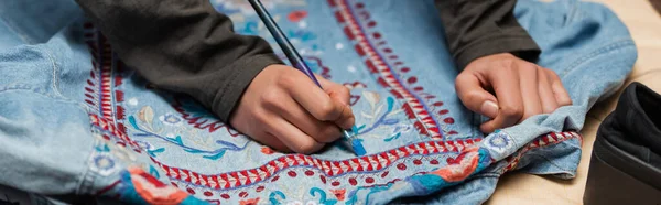 Cropped view of african american craftswoman painting on denim jacket with embroidery, banner — Foto stock