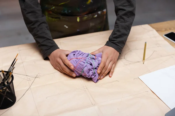 Cropped view of african american designer holding cloth with rubber bands on sewing pattern — Foto stock