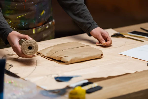 Cropped view of african american craftswoman holding twine near package in workshop — Foto stock