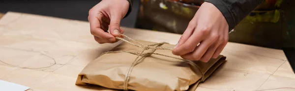 Cropped view of african american designer tying twine on package in workshop, banner — Foto stock