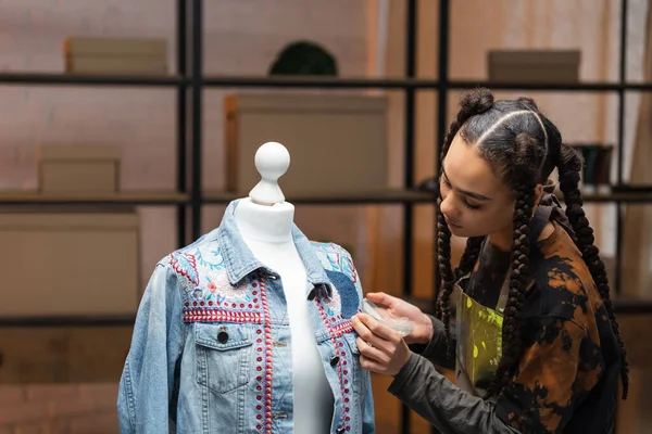 African american designer decorating denim jacket in workshop — Stock Photo