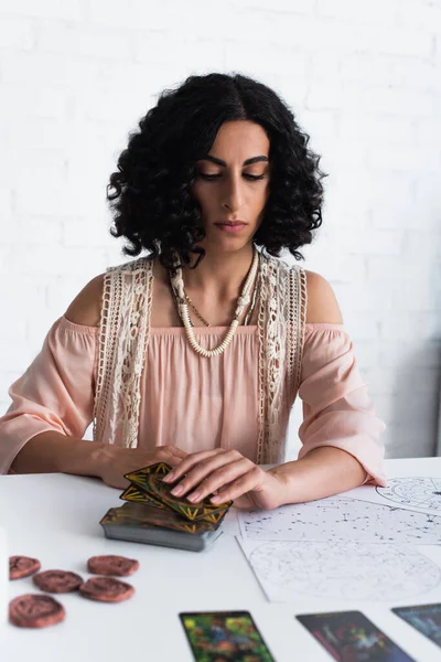 KYIV, UKRAINE - JUNE 29, 2022: brunette fortune teller near tarot cards and celestial maps — Stockfoto