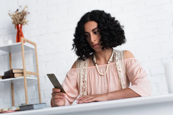 KYIV, UKRAINE - JUNE 29, 2022: thoughtful fortune teller looking at tarot card at home — Photo de stock