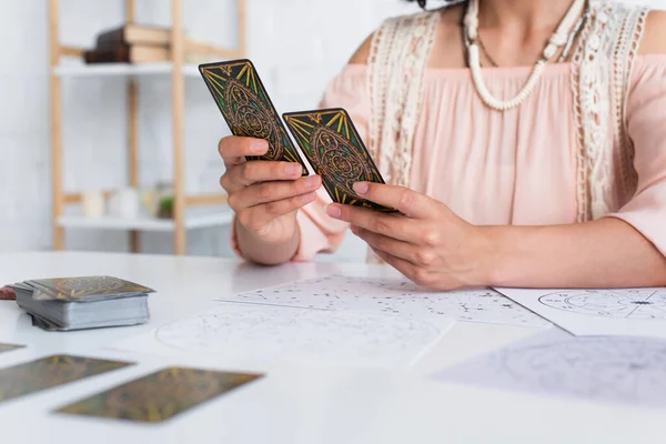 KYIV, UKRAINE - JUNE 29, 2022: cropped view of oracle with tarot cards near star charts on table — Stock Photo