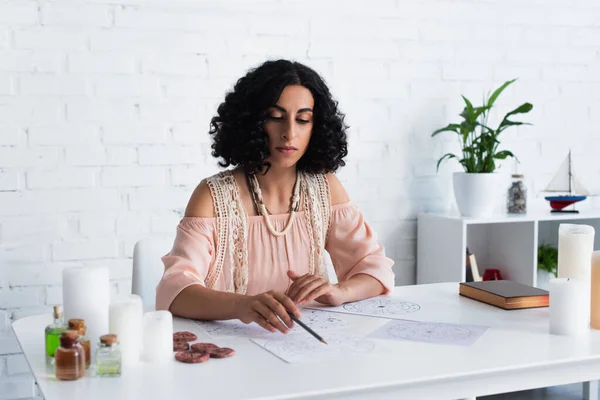 Brunette predictor drawing celestial charts during spiritual session at home — Fotografia de Stock