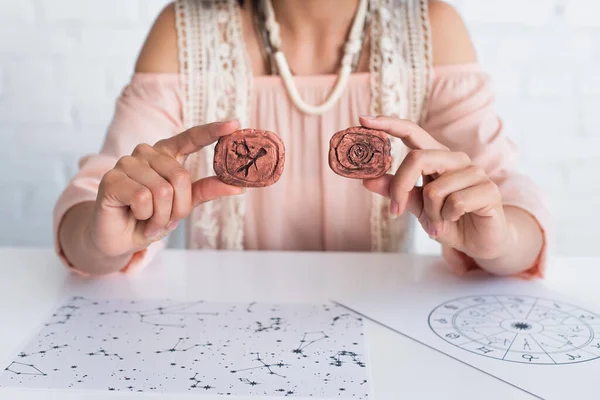 Cropped view of blurred astrologer holding clay runes near star charts — Fotografia de Stock