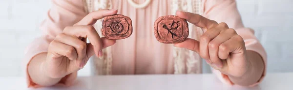 Cropped view of fortune teller holding clay runes while predicting at home, banner — Stockfoto