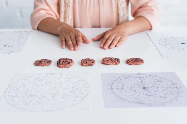 Partial view of astrologist near clay runes and cosmic maps — Stock Photo