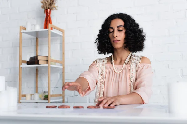 Brunette fortune teller with closed eyes predicting on clay runes — стоковое фото