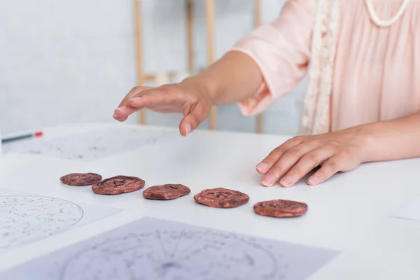 Cropped view of fortune teller near clay runes and cosmic maps during spiritual session — Stock Photo