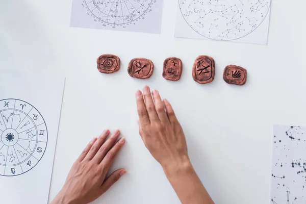 Top view of cropped oracle near clay runes and star charts on table — Foto stock