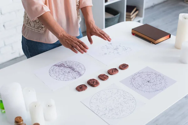 Cropped view of astrological fortune teller near clay runes and celestial charts — Photo de stock