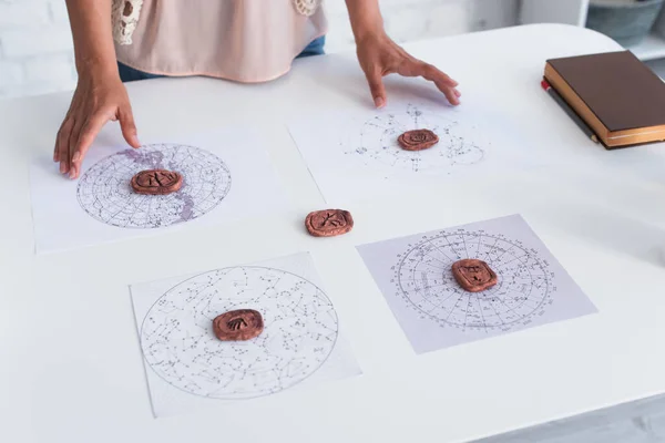 Partial view of young astrologer near clay runes on celestial charts — Fotografia de Stock