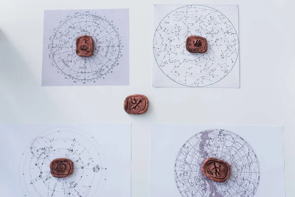 Top view of clay runes and constellation charts on white surface — Stock Photo