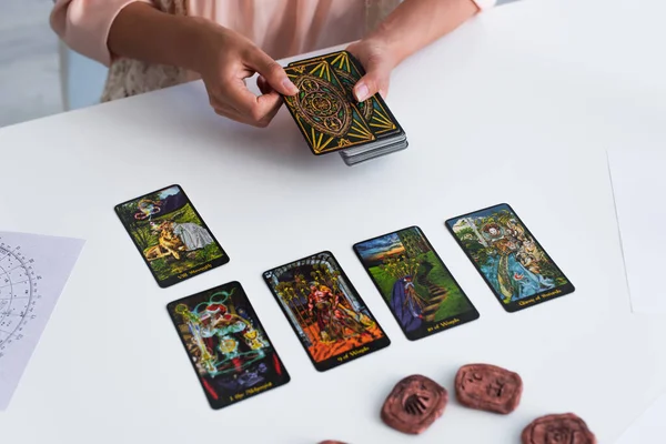 KYIV, UKRAINE - JUNE 29, 2022: top view of tarot cards on table near cropped fortune teller predicting at home — Photo de stock