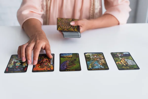 KYIV, UKRAINE - JUNE 29, 2022: cropped view of fortune teller near tarot cards on table — Photo de stock