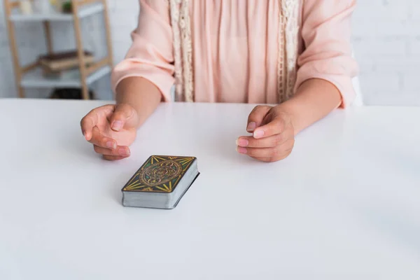 KYIV, UKRAINE - JUNE 29, 2022: cropped view of oracle near deck of tarot cards on table - foto de stock