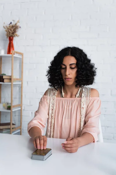 Brunette fortune teller sitting near deck of tarot cards at home — Stock Photo