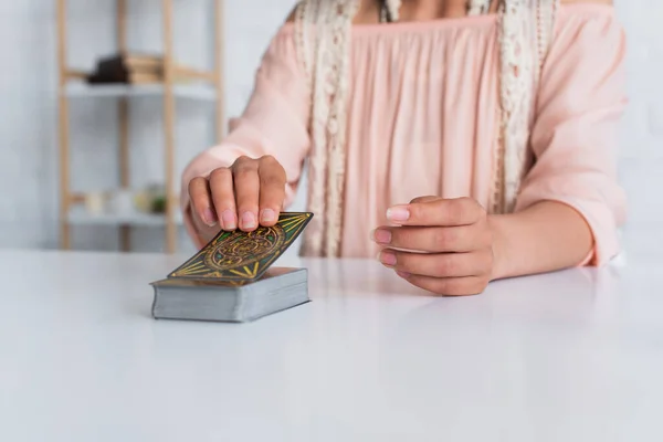 KYIV, UKRAINE - JUNE 29, 2022: cropped view of soothsayer near deck of tarot cards on table - foto de stock